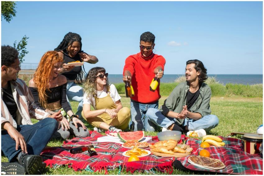 Friends enjoying a sunny picnic by the sea with fo