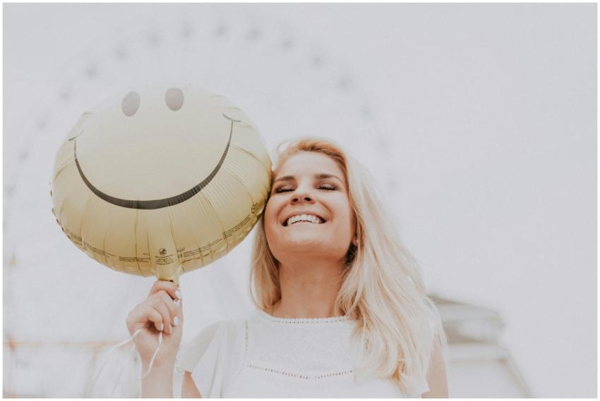 Cheerful woman holding a smiley balloon outdoors o