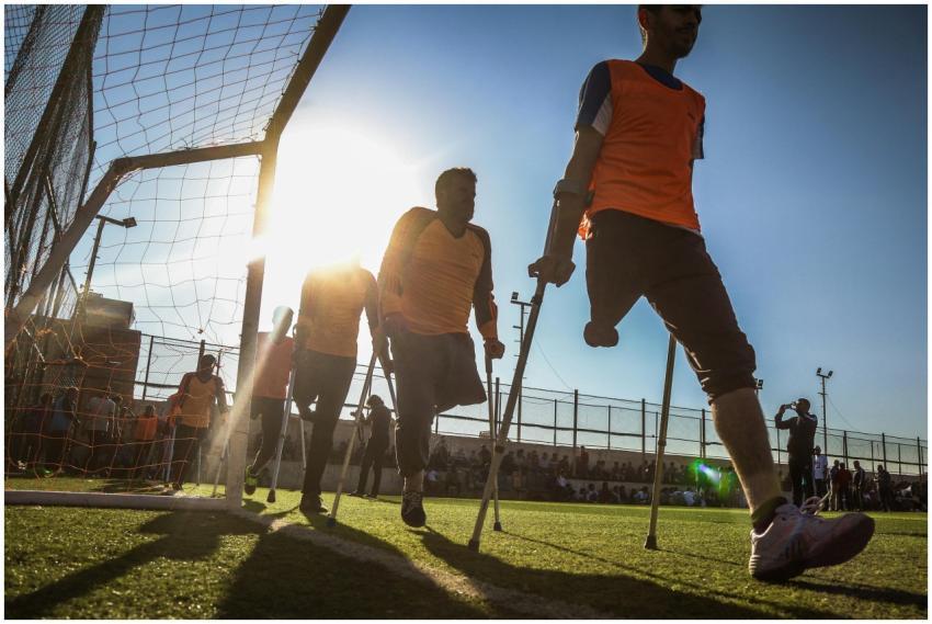 Amputee soccer players in orange jerseys competing