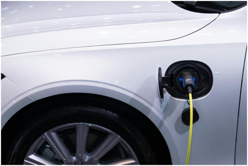 A white electric car is plugged in for charging, c