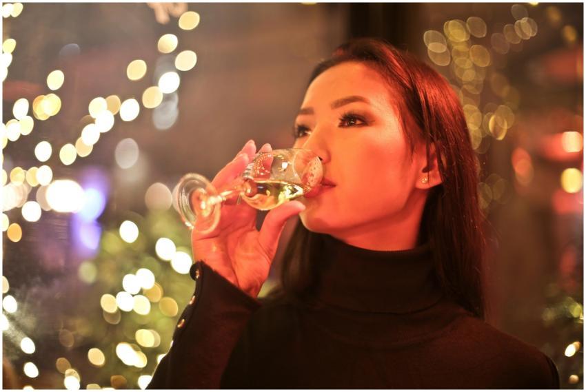 A stylish woman enjoys a glass of wine indoors wit