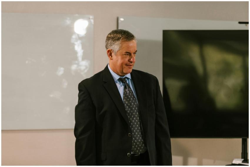Senior man in a suit standing indoors, signifying