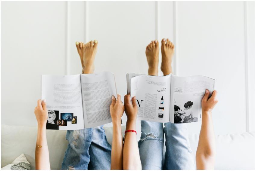 Two people reading magazines upside down in a comf