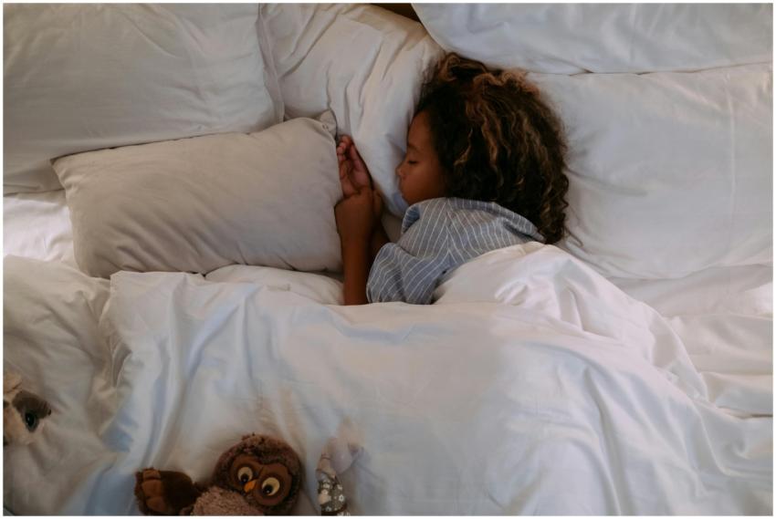 A young girl peacefully sleeping under soft, white