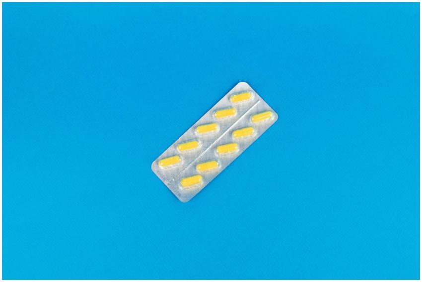 Pack of yellow capsules on a vibrant blue backgrou