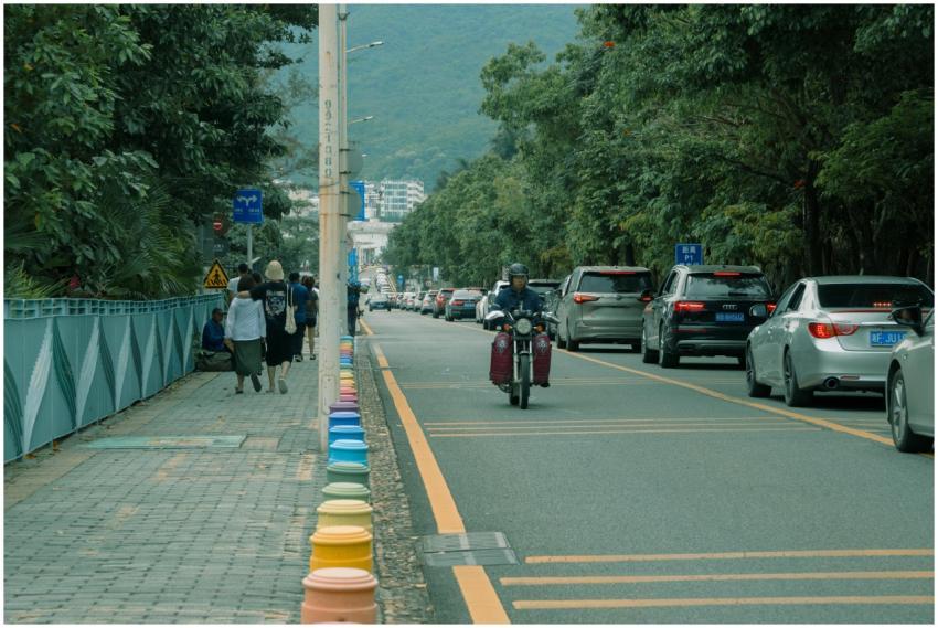 A busy city street with motorbike, cars, and walki