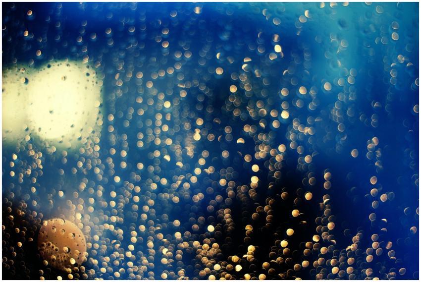 Abstract bokeh lights through a wet window create
