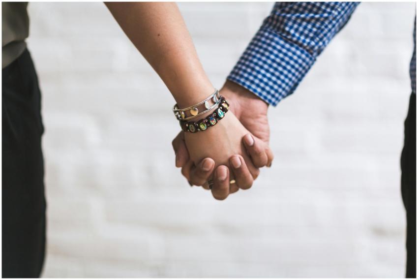 A close-up image of a couple holding hands outdoor