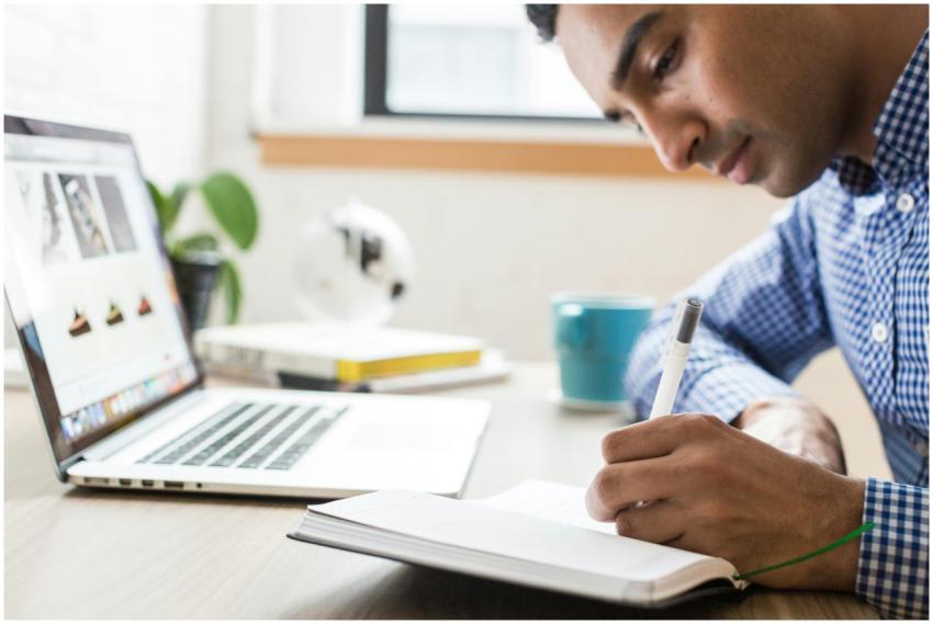 Man focused on writing in a notebook at an office