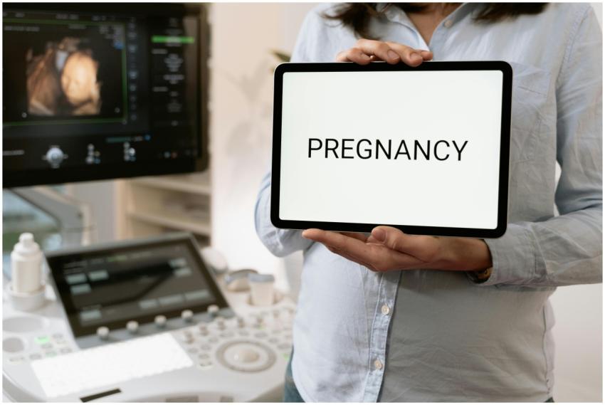 A doctor holding a tablet with 'Pregnancy' near an