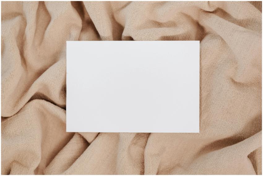 A blank white card on beige textured fabric offeri