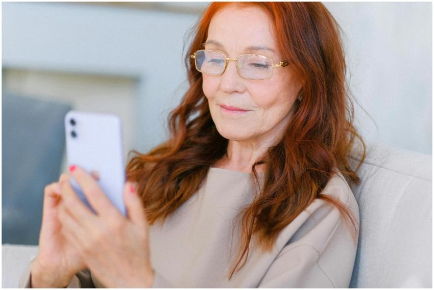 Aged female with red hair in eyeglasses looking at