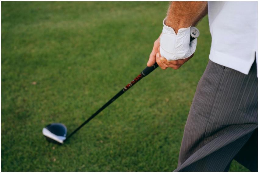 A golfer's hand grips the club firmly, poised for