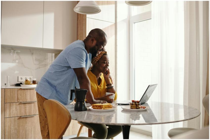 A joyful couple sharing breakfast and working on a
