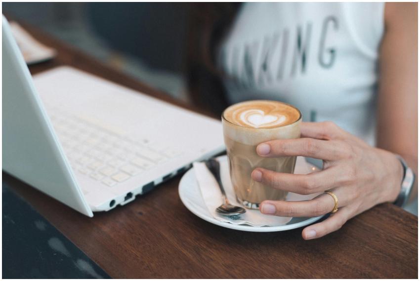 A woman holding a cup of coffee while working on a
