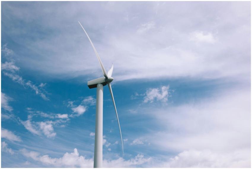 A wind turbine spinning beneath a clear blue sky,