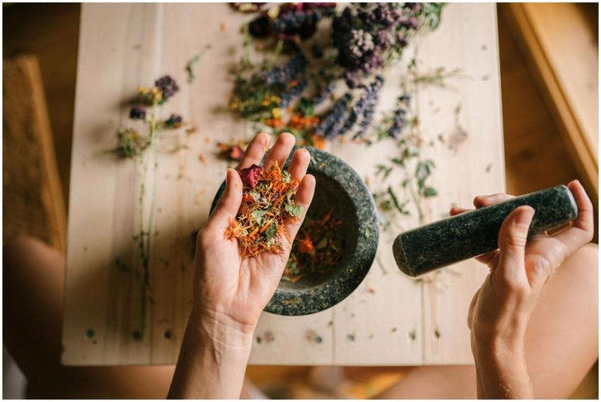 Hands grinding dried herbs with a mortar and pestl