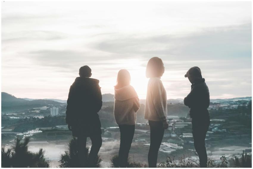 A group of friends standing on a hill, silhouetted