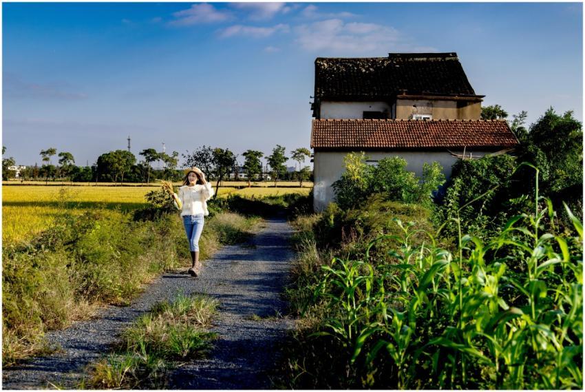 A woman strolls along a country path near a tradit