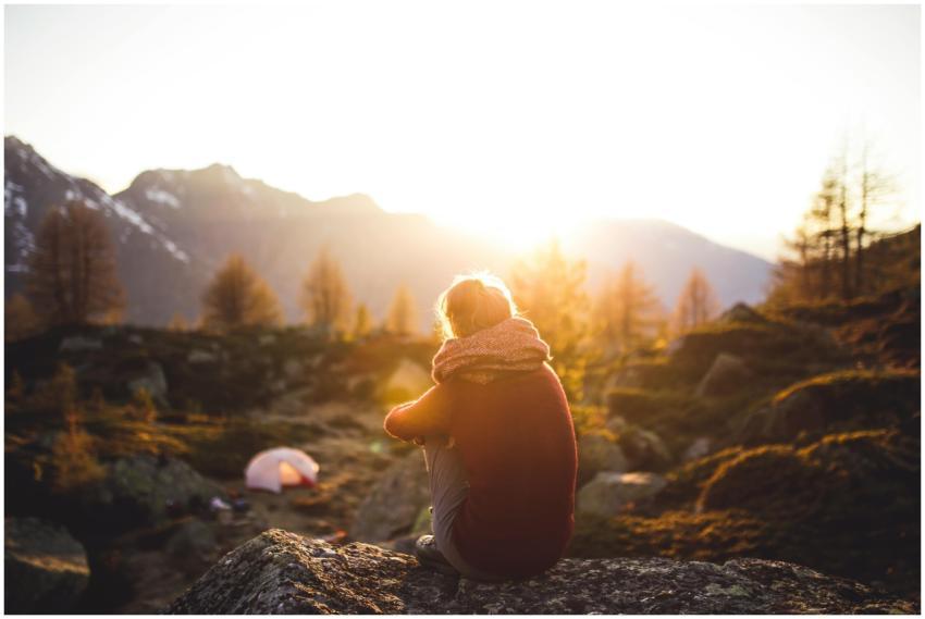 A woman sits on a rock enjoying the serene mountai