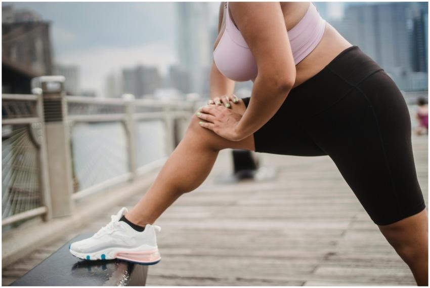 Woman stretching on a city boardwalk in activewear
