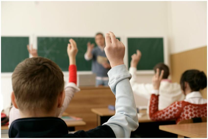 Students in a classroom raising hands, engaging in