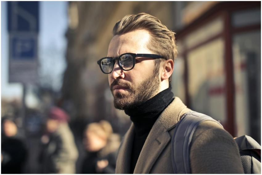 A fashionable man with glasses walks through the v