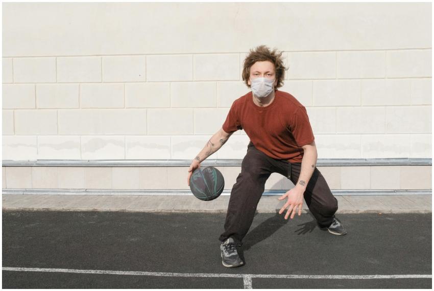 Man playing basketball outdoors while wearing a ma