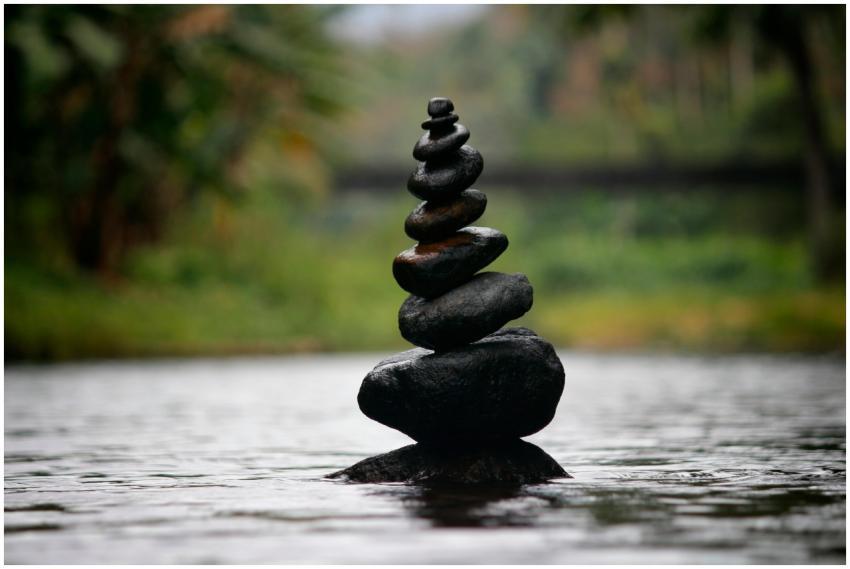 Balanced stones in a serene river evoke a sense of