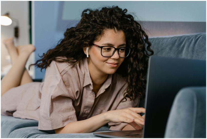 Smiling woman with curly hair and eyeglasses worki