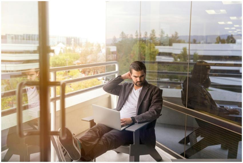 Man working remotely with laptop on office balcony