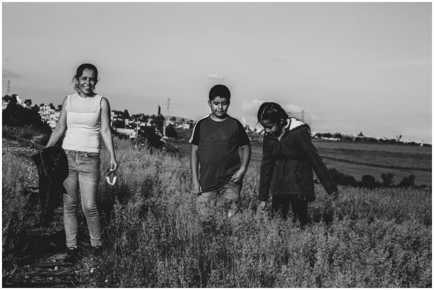 A mother and two children walk through rustic fiel