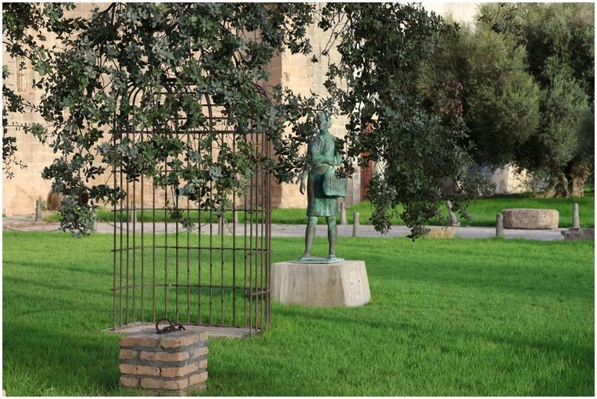 Statue and iron gate surrounded by lush greenery i