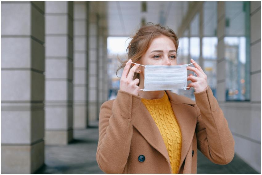 Young woman adjusting her face mask in an urban ou