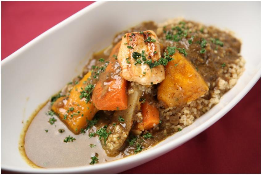 A close-up of a hearty stew featuring grilled meat