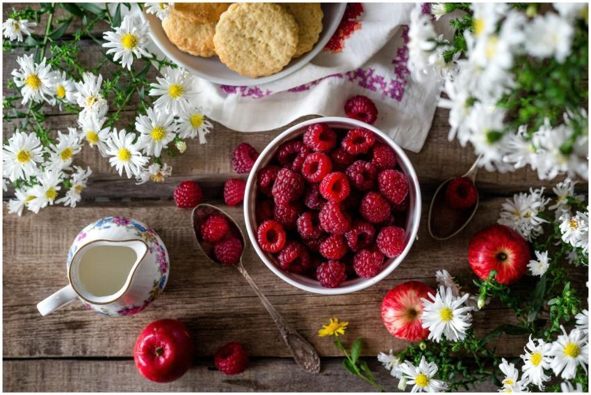 A rustic breakfast scene featuring a bowl of raspb