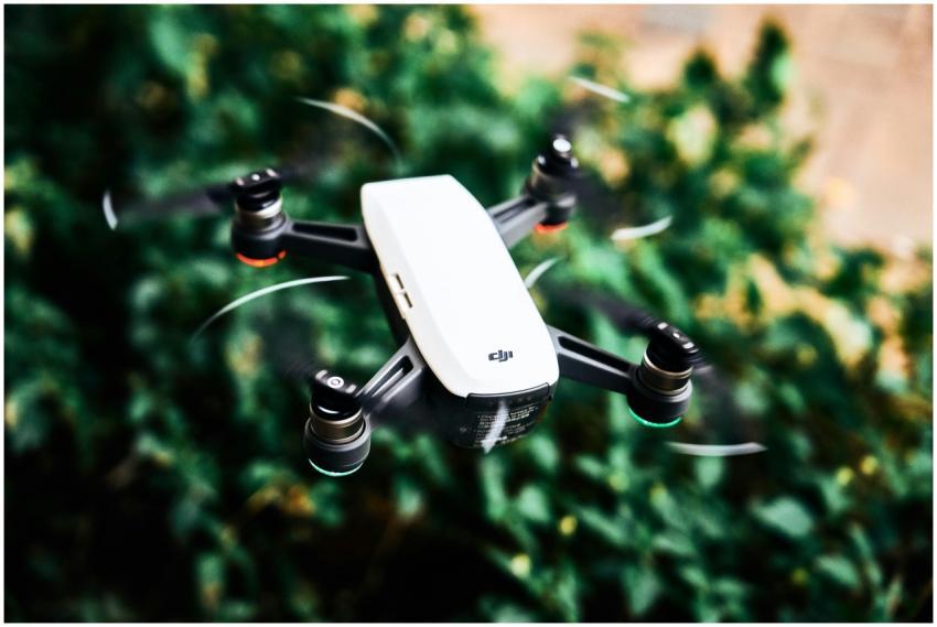 A modern quadcopter flying outdoors over lush gree