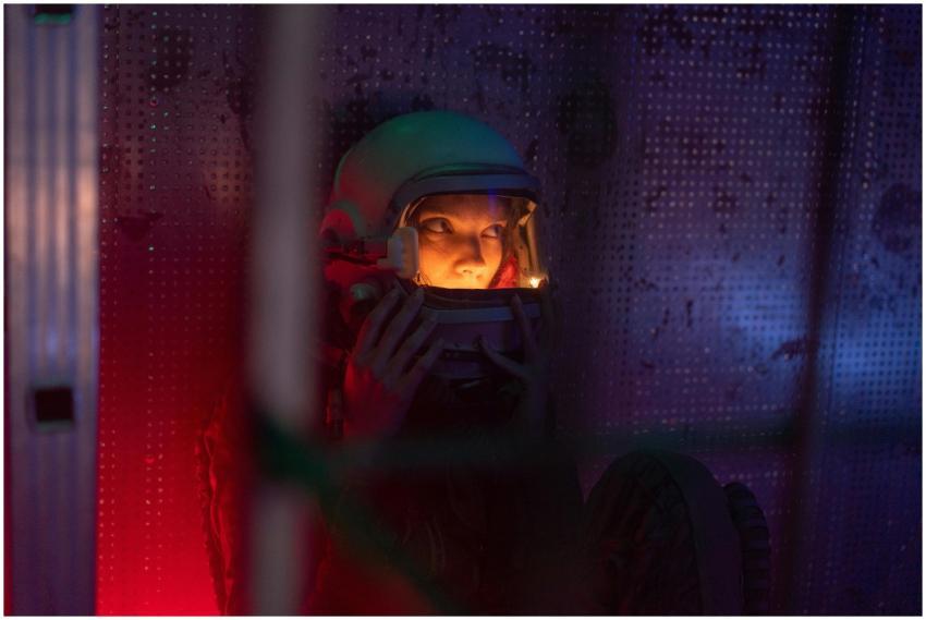 Woman astronaut in a spacesuit sitting in an illum
