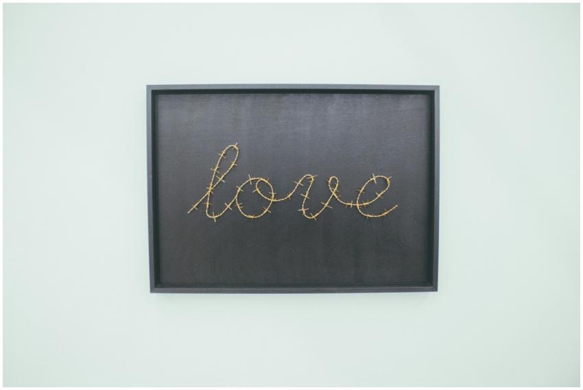 Barbed wire spelling 'love' on blackboard. Minimal