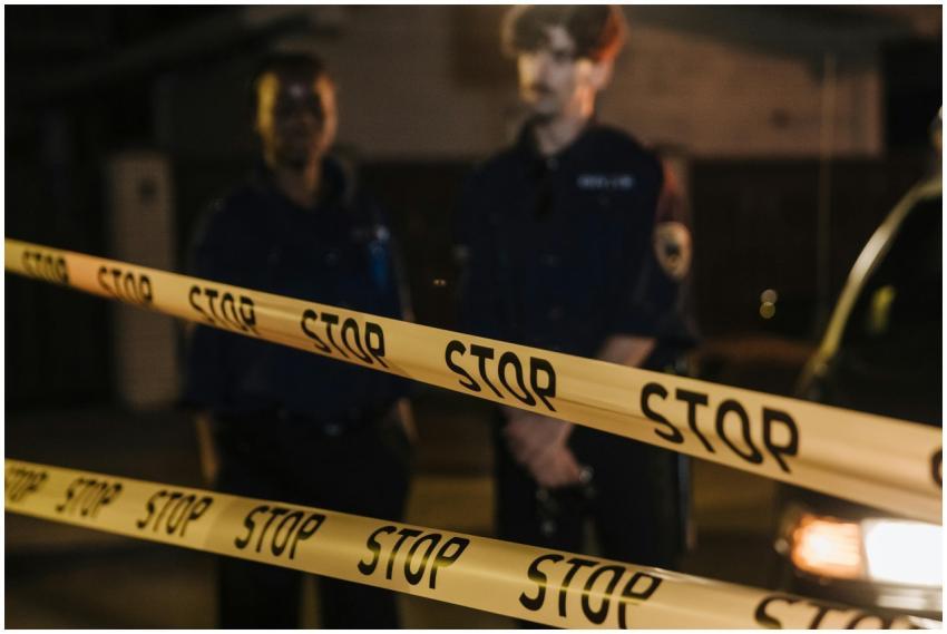 Two police officers standing behind a stop tape at