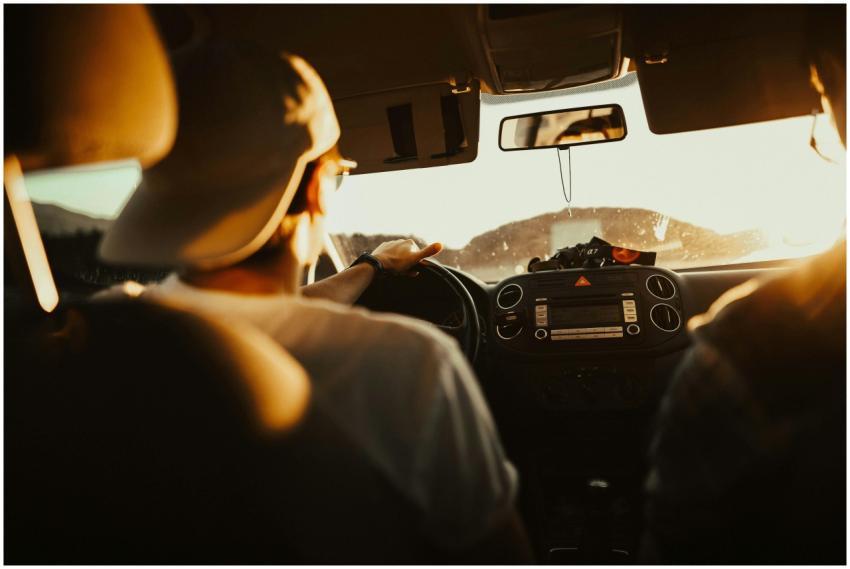 Man driving car with passenger at sunset, capturin
