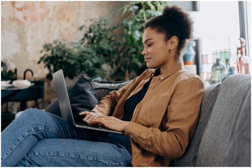 A young woman in casual clothing works on her lapt