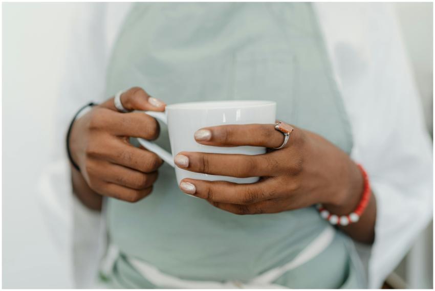 A barista wearing an apron holds a white coffee mu