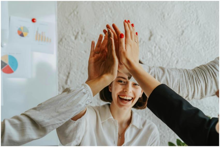 Happy colleagues high-fiving in a meeting, showcas