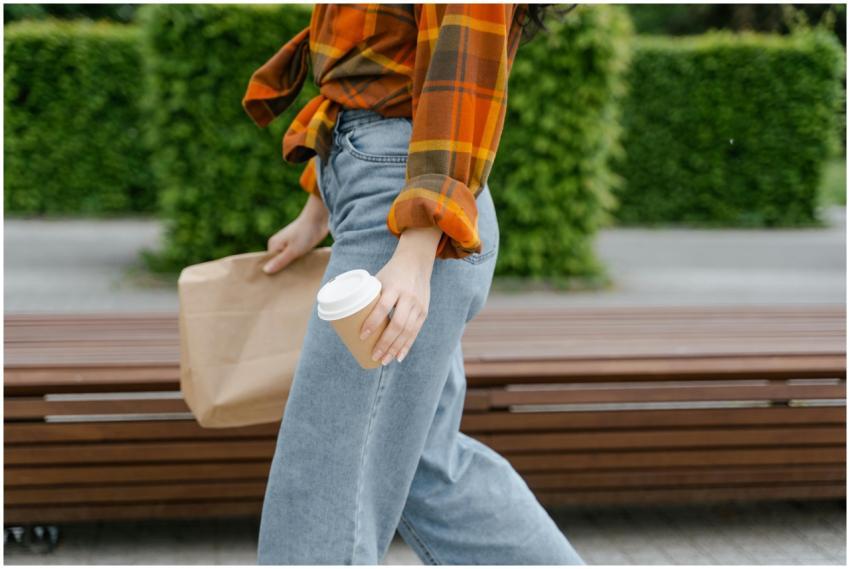 Woman walking outdoors holding a coffee cup and br