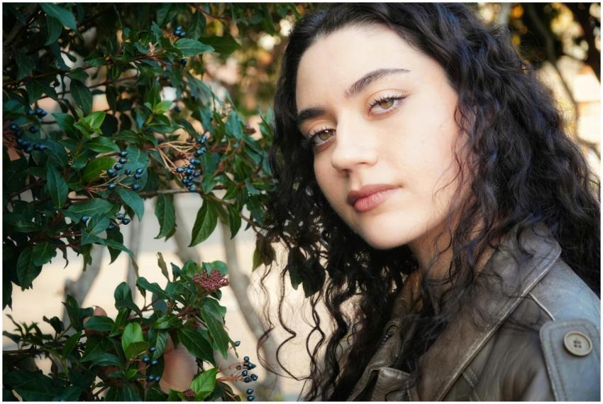Portrait of a young woman with curly hair beside l
