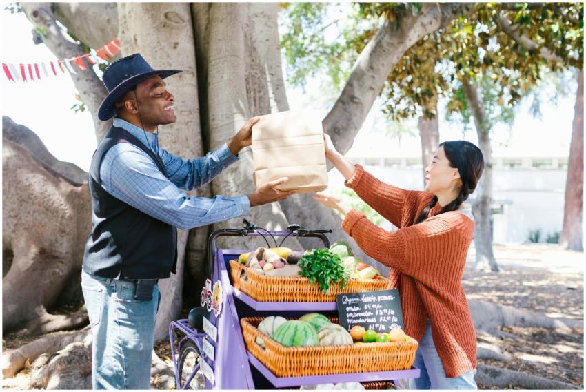 A vendor hands a paper bag to a customer at an out