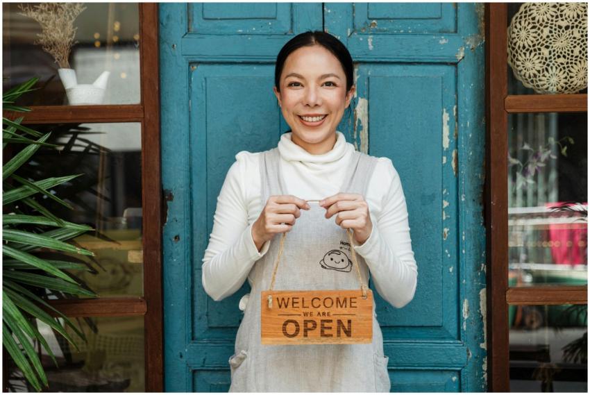 Cheerful ethnic female cafeteria owner in apron de