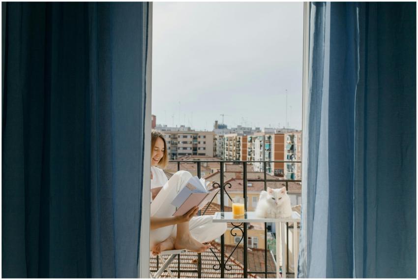 A woman enjoys reading on her balcony with a white
