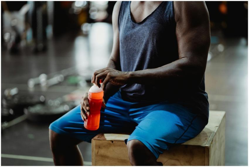 Muscular man taking a break with a sports drink in